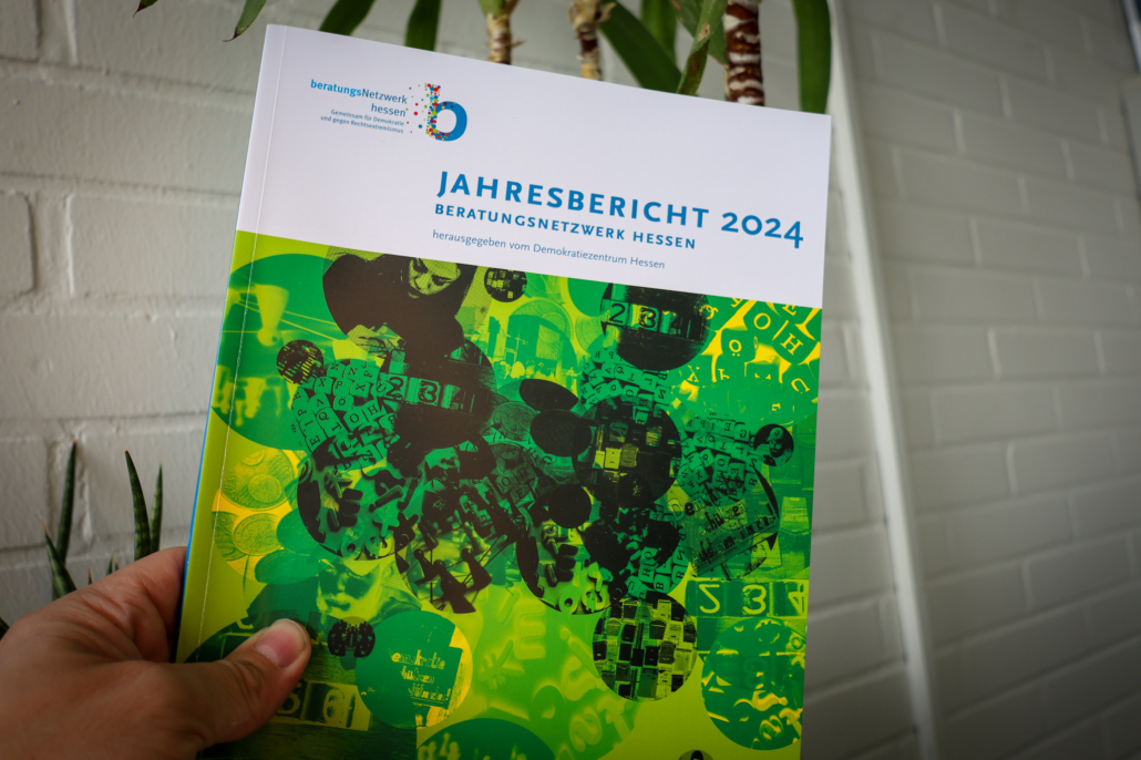 Bild einer Hand, die den Jahresbericht 2024 des "Beratungsnetzwerk Hessen - Gemeinsam für Demokratie und gegen Rechtsextremismus" hält.